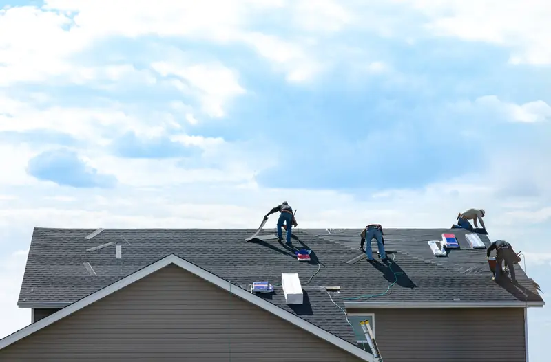 Four roofers working across a large pitched roof under a blue sky